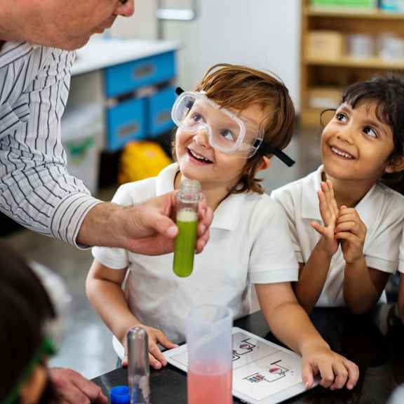 Themabeeld van Triodos Future Generations Fund waarop 3 kinderen en een volwassene met scheikunde bezig zijn