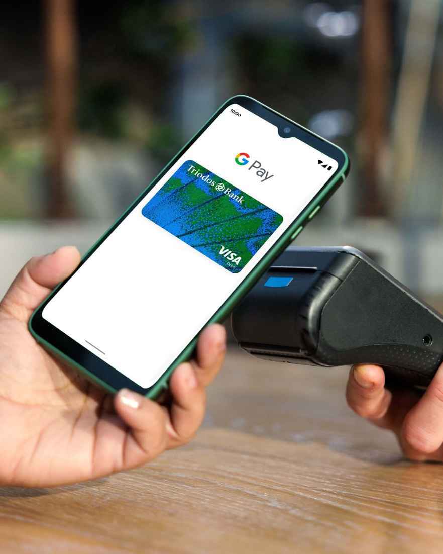 Iemand betaalt met de Triodos Betaalpas via Google Pay op mobiel in een winkel