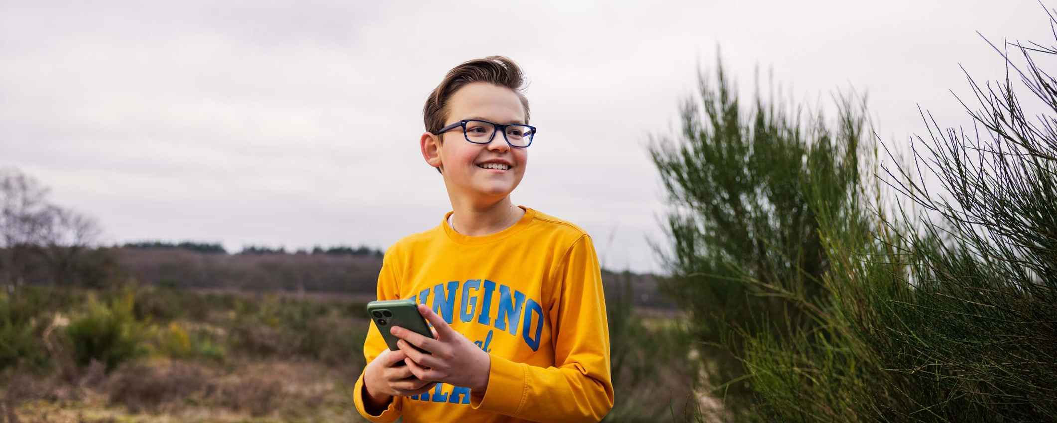 Jongen met telefoon in de natuur