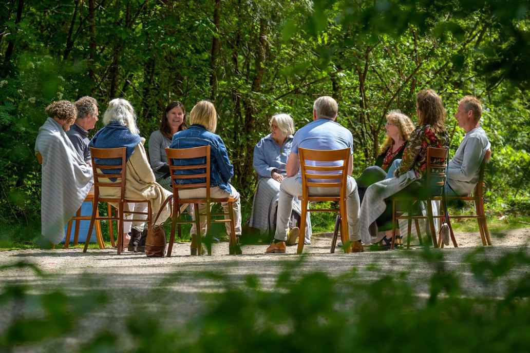 Mensen zitten buiten in een kring te praten. Beeld van The Gift 2022